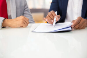Dos personas revisando un contrato con un bolígrafo sobre una mesa